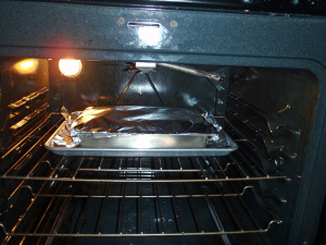 Covered Lasagna on Cookie Sheet Placed in Oven by Connie Cockrell